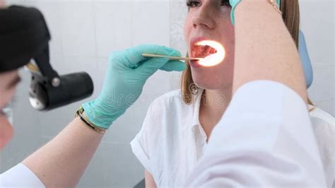 A Female Otolaryngologist Examines The Patient S Oral Cavity With A