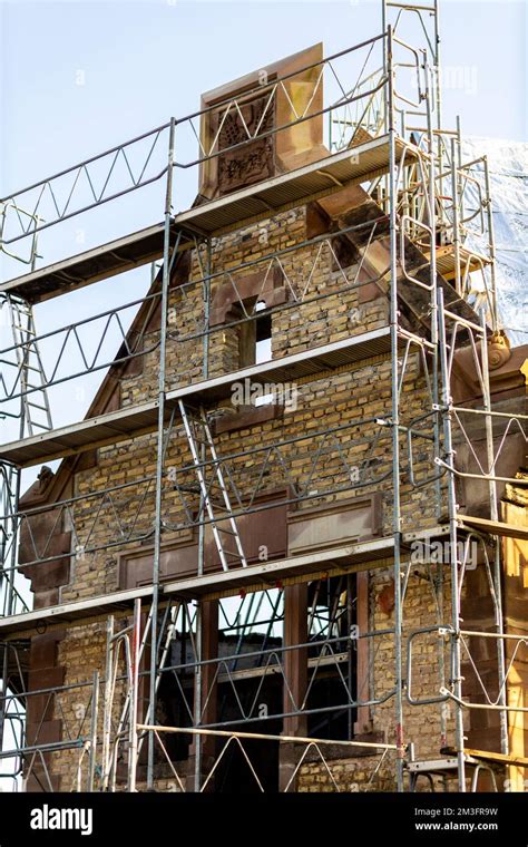 A Vertical Shot Of An Old Masonry Building Covered In Scaffolding Stock