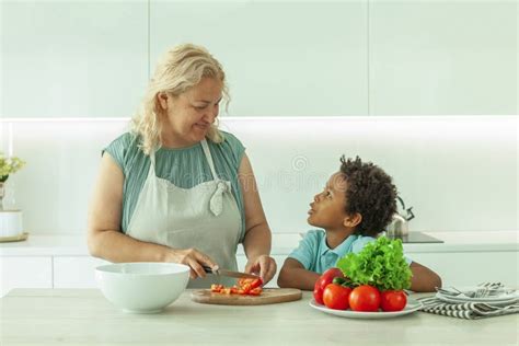 Cute Mature Woman And Her Son Preparing Healthy Food Together Standing At A Worktop In The