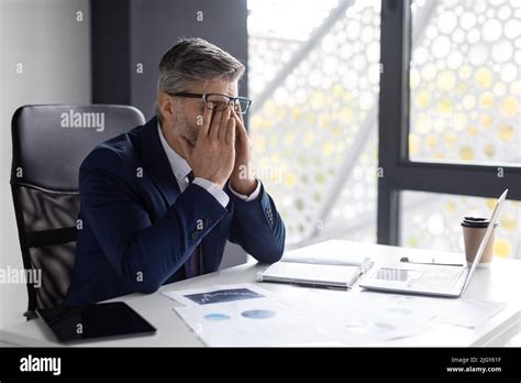 Job Burnout Exhausted Mature Businessman Sitting At Workplace And