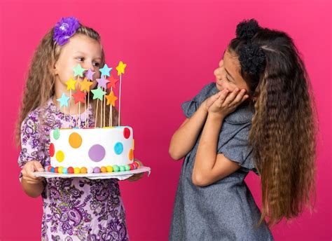 Free Photo Pleased Little Caucasian Girl Looking At Little Blonde Girl Holding Birthday Cake