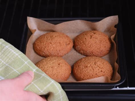 Woman Taking A Baking Tray With Four Oatmeal Cookies On It Out Of An
