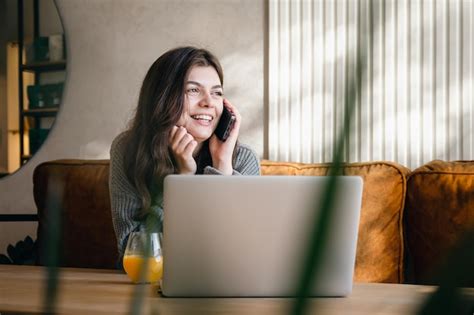 Mulher Jovem E Atraente Falando Ao Telefone E Trabalhando Em Um Laptop