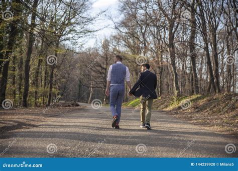 Vista Trasera Dos Gay Caminando En El Bosque En La Carretera Asfaltada Foto De Archivo