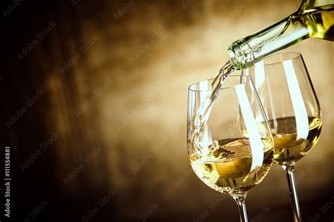 Pouring two glasses of white wine from a bottle Stock Photo | Adobe Stock