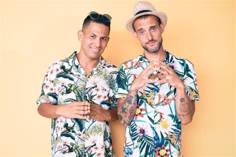 La Joven Pareja Gay De Dos Hombres Con Sombrero De Verano Y Camiseta Hawaiana De Las Manos