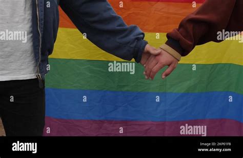 Homosexual Men Holding Hands With Gay Pride Flag On Background