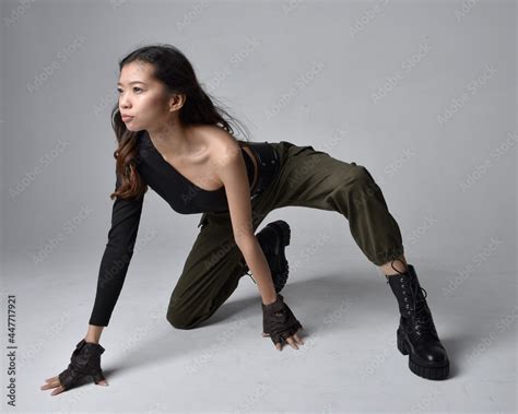 Full Length Portrait Of Pretty Brunette Asian Girl Wearing Black Top And Khaki Utilitarian Army