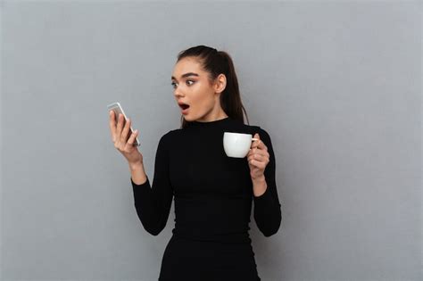 Free Photo Shocked Brunette Woman In Black Clothes Looking At Smartphone