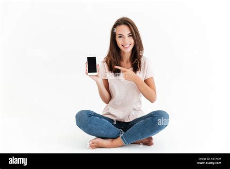Smiling Brunette Woman Showing Blank Smartphone Screen And Pointing At