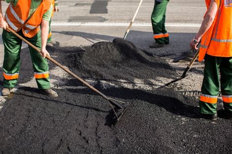 Los trabajadores de la máquina pavimentadora de asfaltado durante los