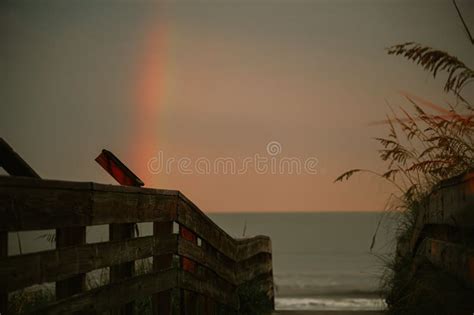 Serene Beach Scene With A Wooden Walkway Leading To The Ocean In