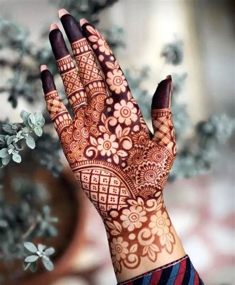 A Woman S Hand With Henna On It And Some Flowers In The Background