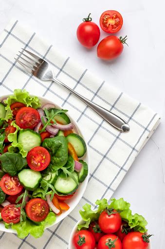 회색 대리석 배경에 흰색 접시에 야채 맨 위 보기입니다 체리 토마토 오이 아루굴라 바질 올리브 오일로 만든 샐러드 건강한 음식