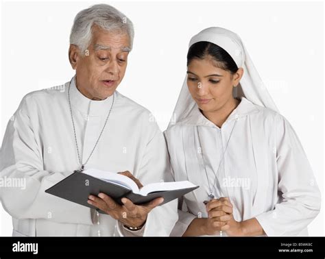 Priest And A Nun Looking At The Bible Stock Photo Alamy