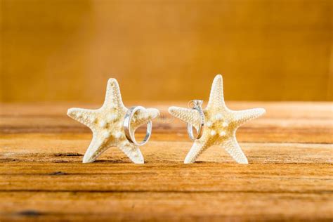 Two Wedding Rings With Two Starfish On Wooden Table Stock Photo Image