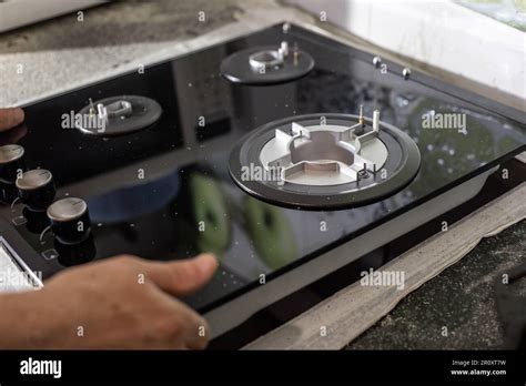 A Man Installs A Built In Glass Ceramic Gas Stove On A Kitchen