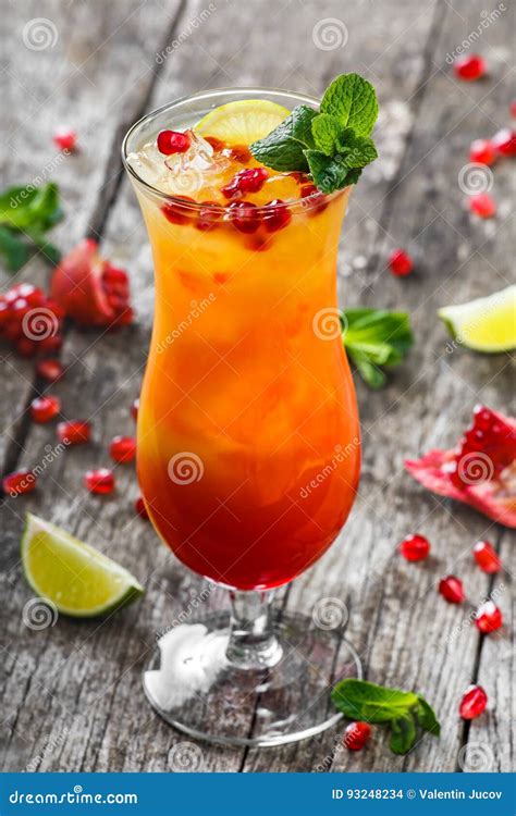 Fresh Fruit Tropic Cocktail With Mint Orange And Pomegranate In Tall Glass On Wooden Background