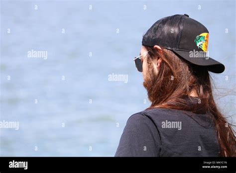 Young Man With Very Long Straight Hair And Beard Wearing A Baseball Cap From Bass Pro Shop He