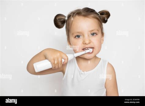 Petite jolie fille blonde se brossant les dents avec une brosse à dents électrique Soins