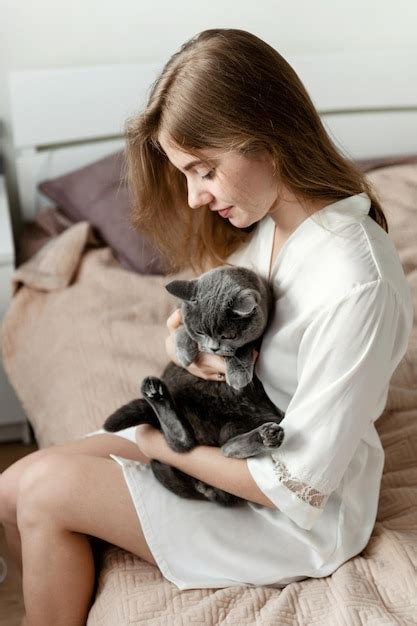 Premium Photo A Sexy Girl In Thin Pajamas Sits On The Bed And Holds A Beautiful Scottish Cat