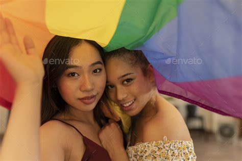 Two Women Wrapped In The Pride Flag Multiracial Asian And Hispanic Lesbian Couple Stock Photo