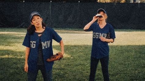 Two Women Are Standing In The Grass And One Is Holding A Baseball Mitt