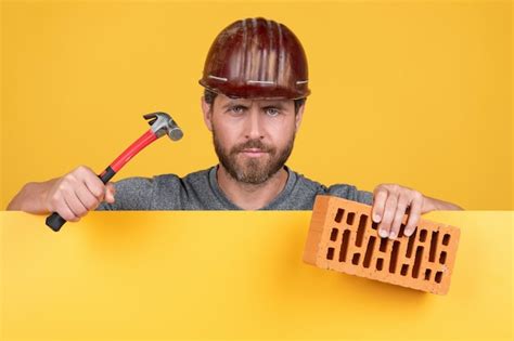 Premium Photo Bricklayer Mature Man In Helmet With Hammer And Brick