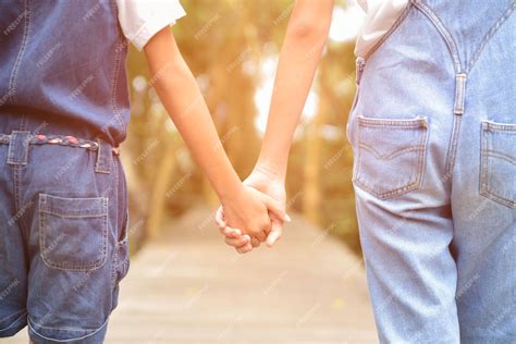 Premium Photo Two Children Holding Hands Each Other On The Wooden Way