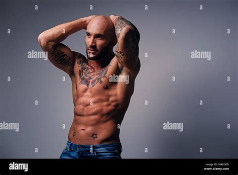 Studio Portrait Of Shirtless Shaved Head Muscular Male With Tattoos On