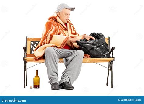 Homeless Mature Man Sitting On A Bench And Looking For Something Stock