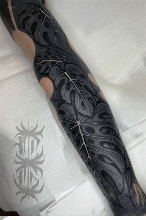 A Man S Arm Covered In Black Ink With An Intricate Design On The Arm