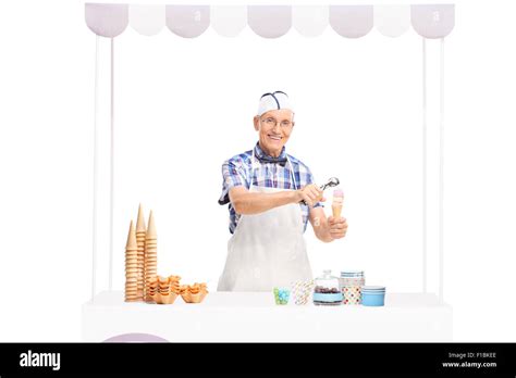 Mature Ice Cream Seller Making An Ice Cream Behind A Stall And Looking At The Camera Isolated On
