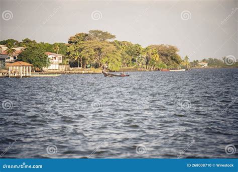 Boat On The Sea Surface With Trees And Houses On The Coast In Puerto