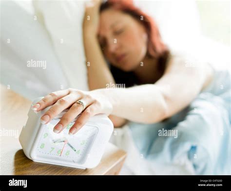 Woman Turning Off Alarm Clock Stock Photo Alamy