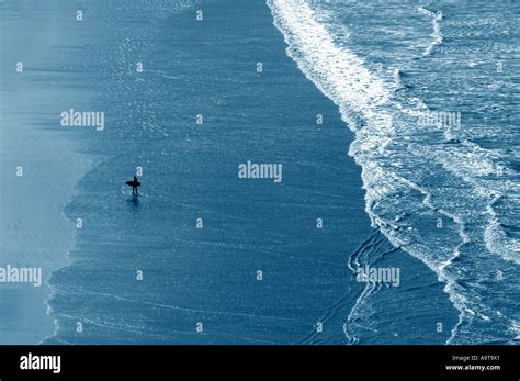 Silhouetted Surfers Pictured Against An Almost Metallic Reflection Of