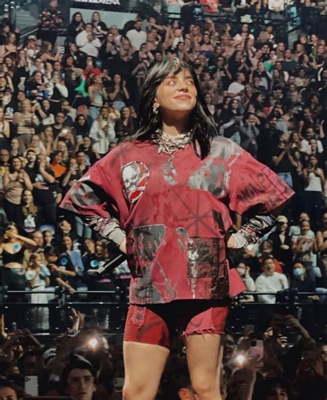 A Woman Standing On Top Of A Stage In Front Of A Large Group Of People