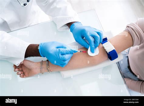 Close Up Of Female Doctor Injecting Male Patient With Syringe To