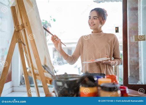 Asian Female Painter Painting On Canvas In Her Workshop Stock Photo