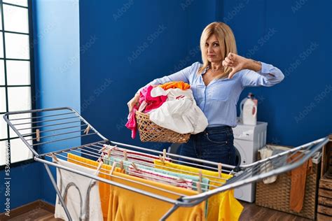 Middle Age Blonde Woman Putting Clean Clothes At Clothesline With Angry Face Negative Sign