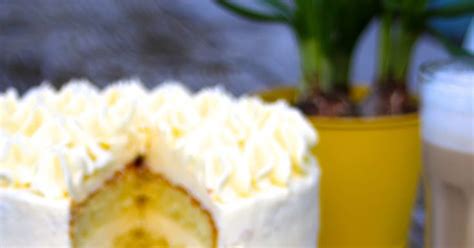 A Close Up Of A Cake With White Frosting On A Table Next To A Potted Plant