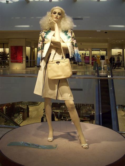 A Mannequin Dressed In White Holding A Handbag