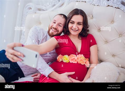 A Husband And A Pregnant Wife Make Selfie Sitting On The Couch They