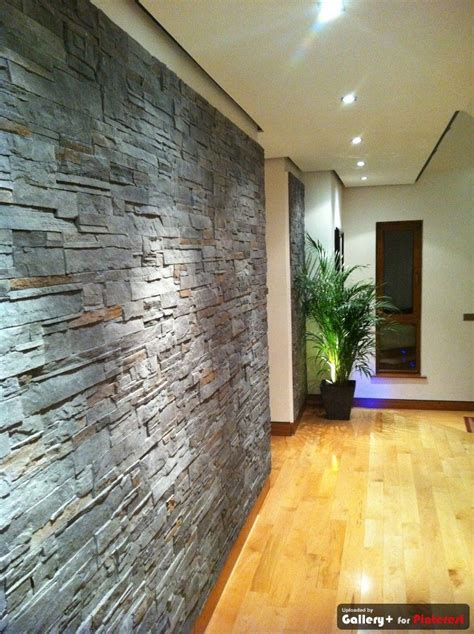 a room with wood floors and a stone wall in the center, along with a ...