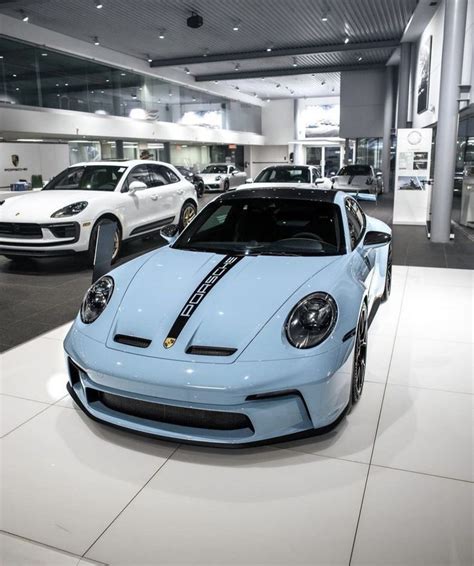 There Are Many Cars On Display In The Showroom And One Is Light Blue