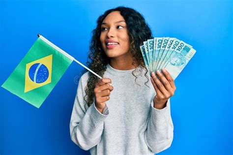 Jovem Latina Segurando Bandeira Brasileira E Notas De Verdade Sorrindo Olhando Para O Lado E
