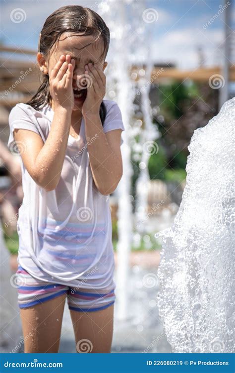 A Little Wet Girl is Cooling Off in a Fountain on a Hot Summer Day ...