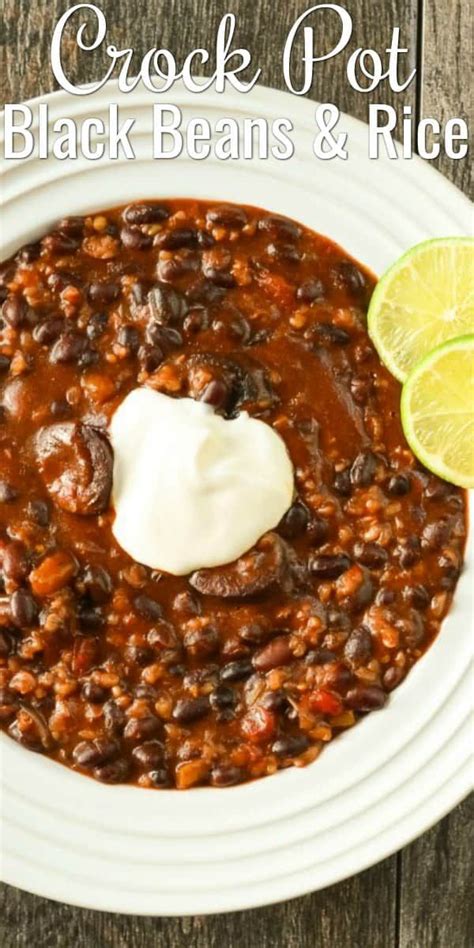 A White Bowl Filled With Black Beans And Rice Next To A Lime Slice On The Side