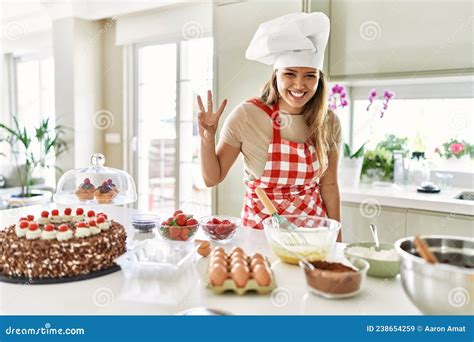 Beautiful Young Brunette Pastry Chef Woman Cooking Pastries At The Kitchen Showing And Pointing