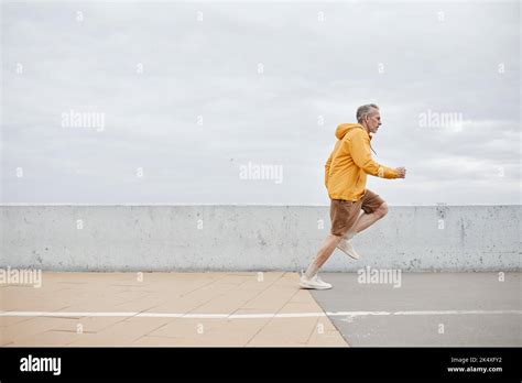 Minimal Side View Portrait Of Sportive Mature Man Running By River